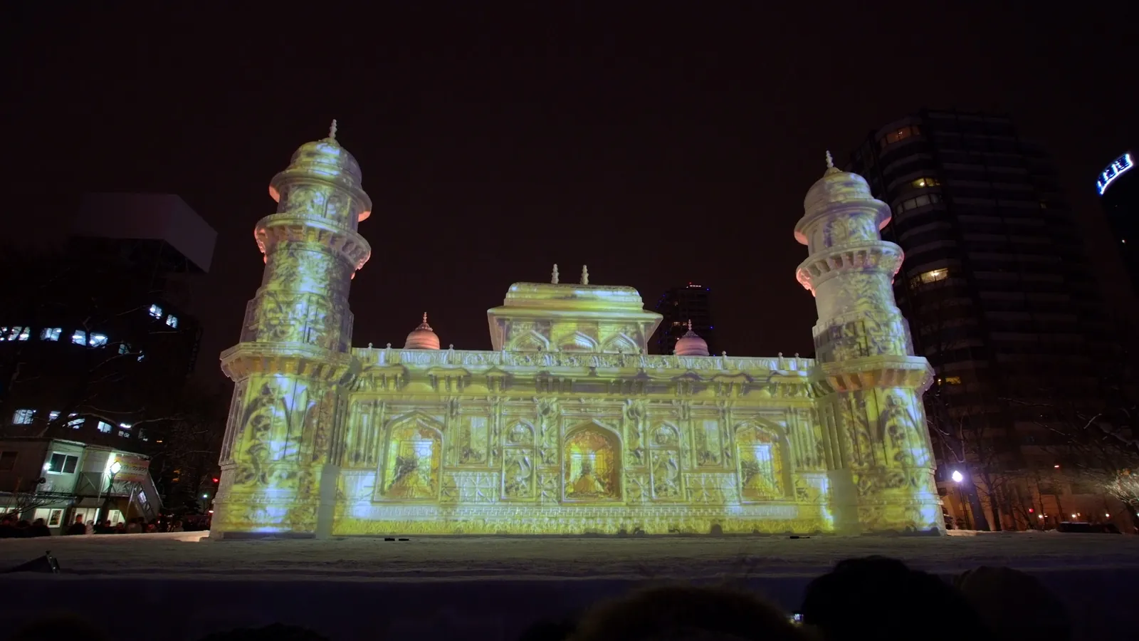 A snow sculpture of a palace lit up at night at the Sapporo Snow Festival