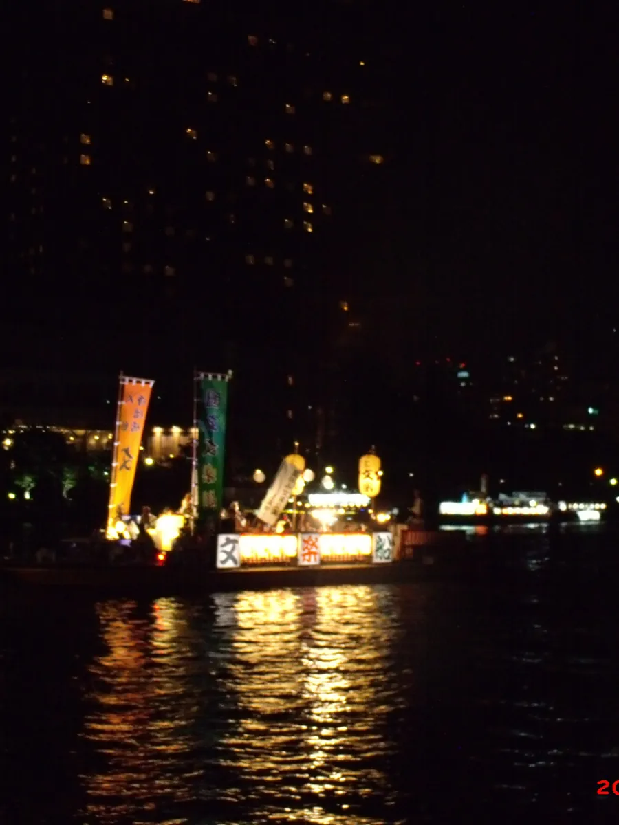 An illuminated float boat on the Okawa River at night during Tenjin Matsuri